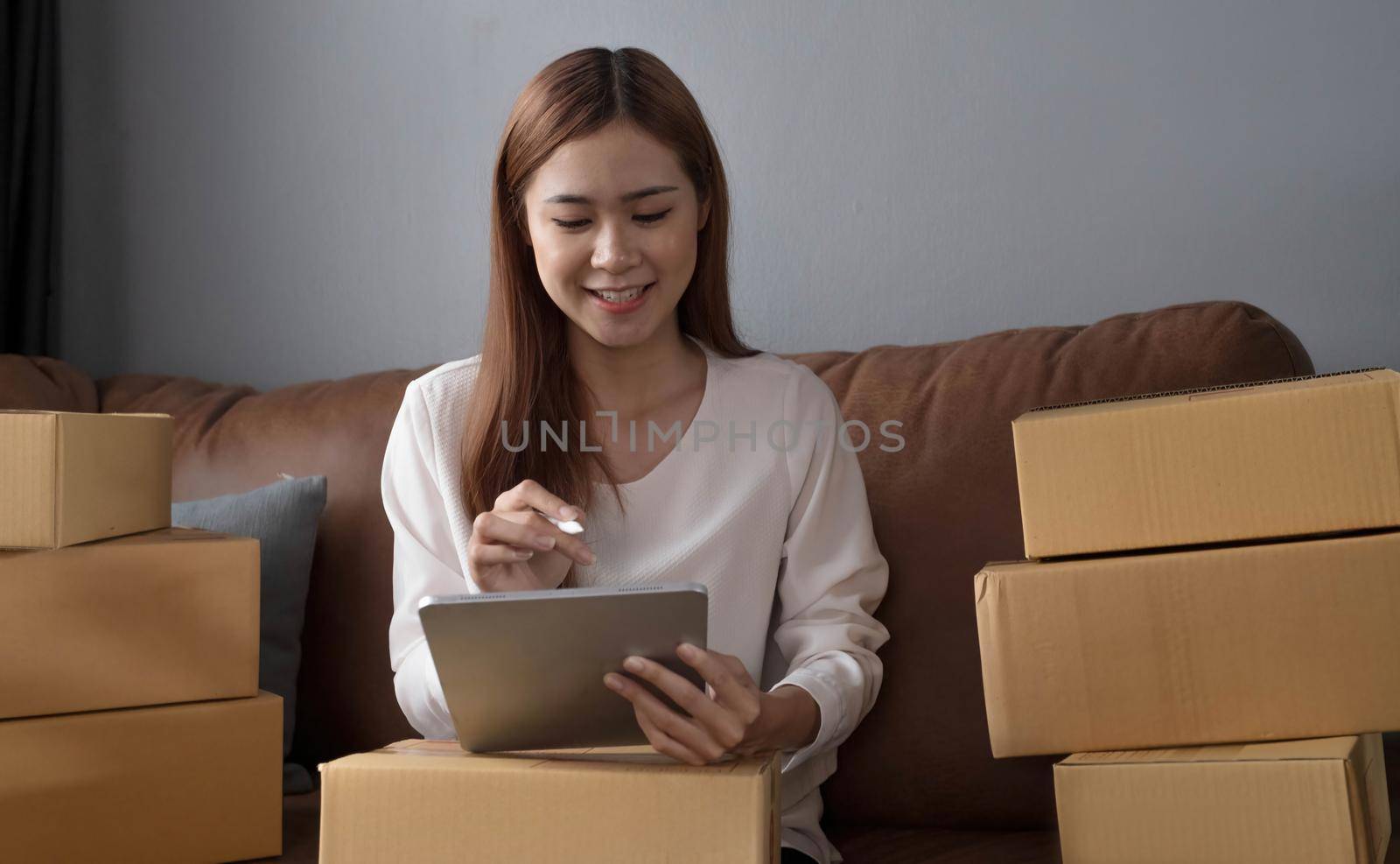 Starting small businesses SME owners female entrepreneurs Use a laptop or notebook to receive and review orders online to prepare to pack boxes, sell to customers, SME online business ideas. by wichayada