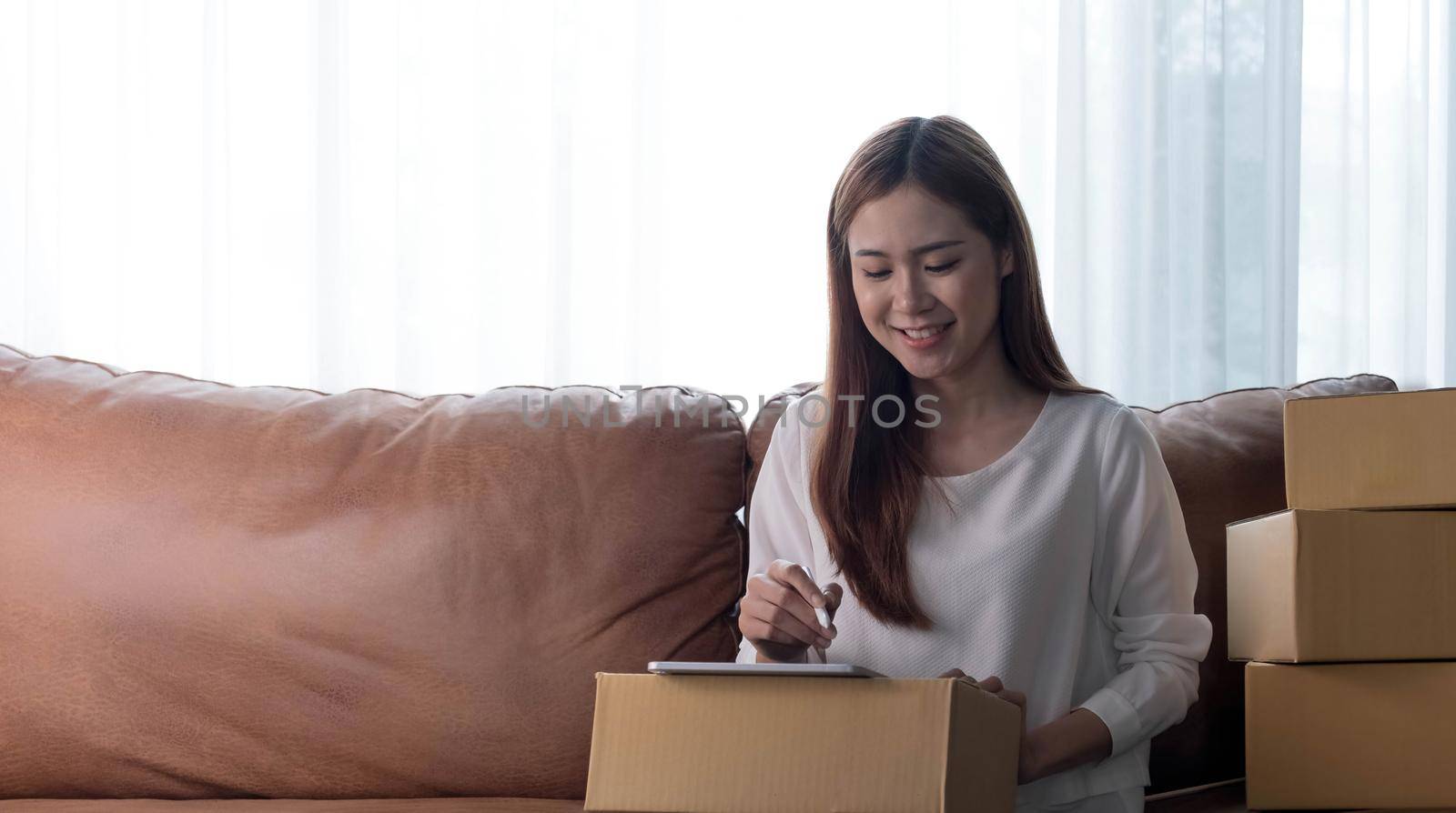 Starting small businesses SME owners female entrepreneurs Use a laptop or notebook to receive and review orders online to prepare to pack boxes, sell to customers, SME online business ideas..