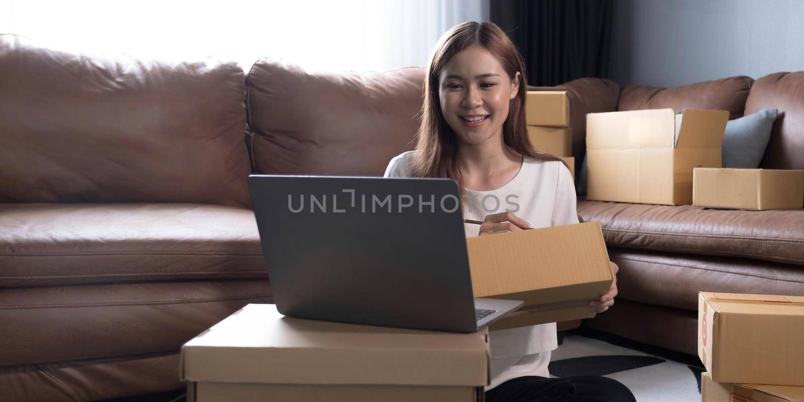 Shipping shopping online ,young start up small business owner writing address on cardboard box at workplace.small business entrepreneur SME or freelance asian woman working with box at home.