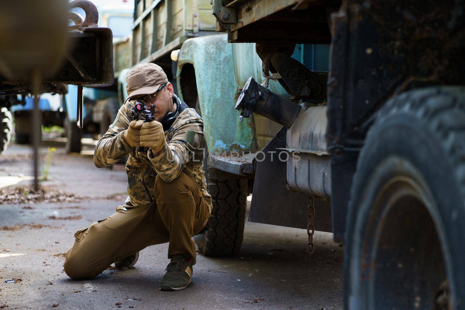 Young man in tactical training course. Outdoor shooting range. Private military contractor at tactical training course. Defensive tactics shooter course, man with a gun in military uniform.