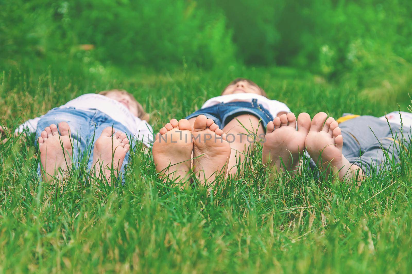 Children's feet on the green grass in the park. Selective focus. by yanadjana