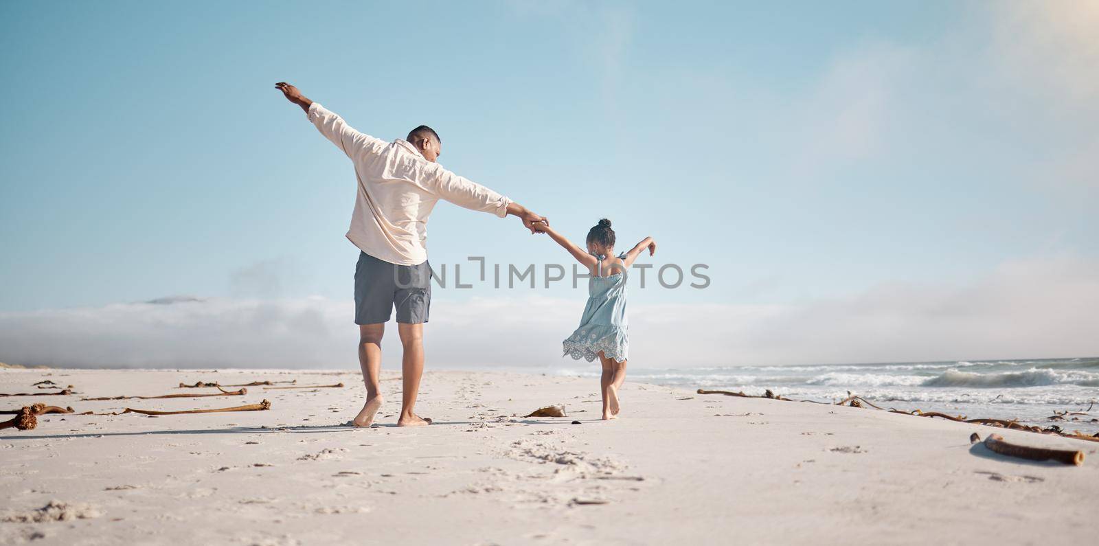 Full length rearview of unknown mixed race single father holding little daughters hand with copyspace. Adorable, hispanic girl walking and bonding with parent. Man and child enjoying beach free time.