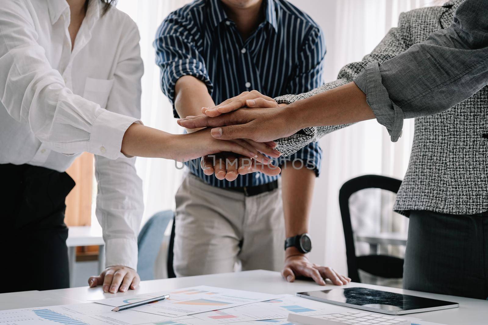 Close up happy diverse business people putting hands together, showing support and unity. Multiracial colleagues involved in team building activity. Staff training concept, start working together