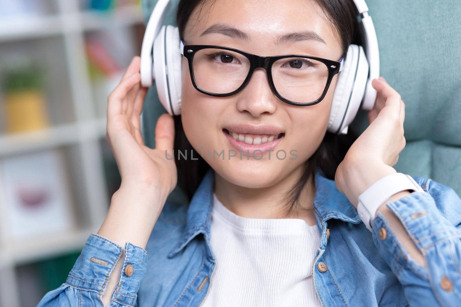 Portrait of a young Asian teenage girl listening to music in white headphones photo close up portrait.