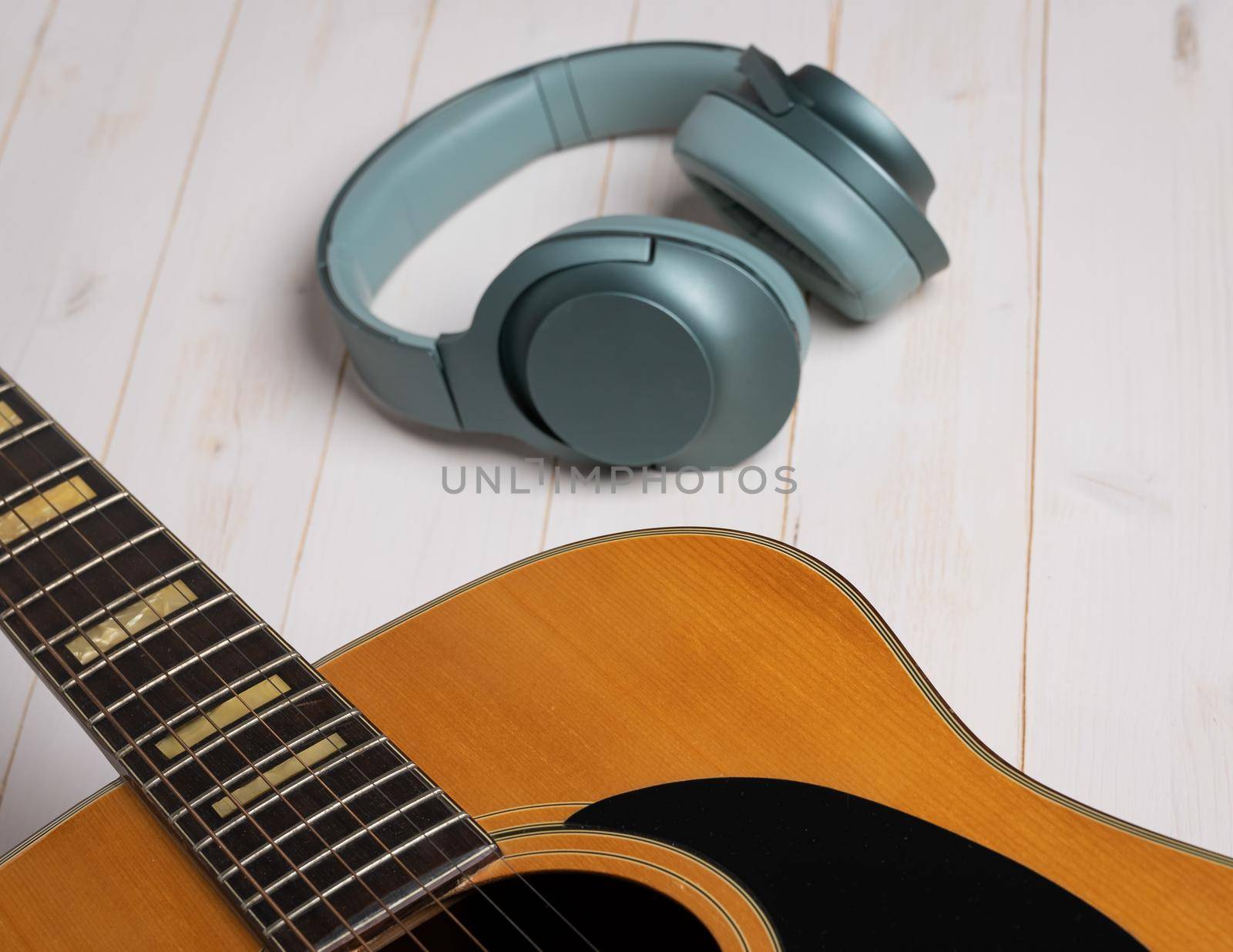 Music recording scene with guitar, empty music sheet, pencil and headphones on white wooden table by Robertobinetti70