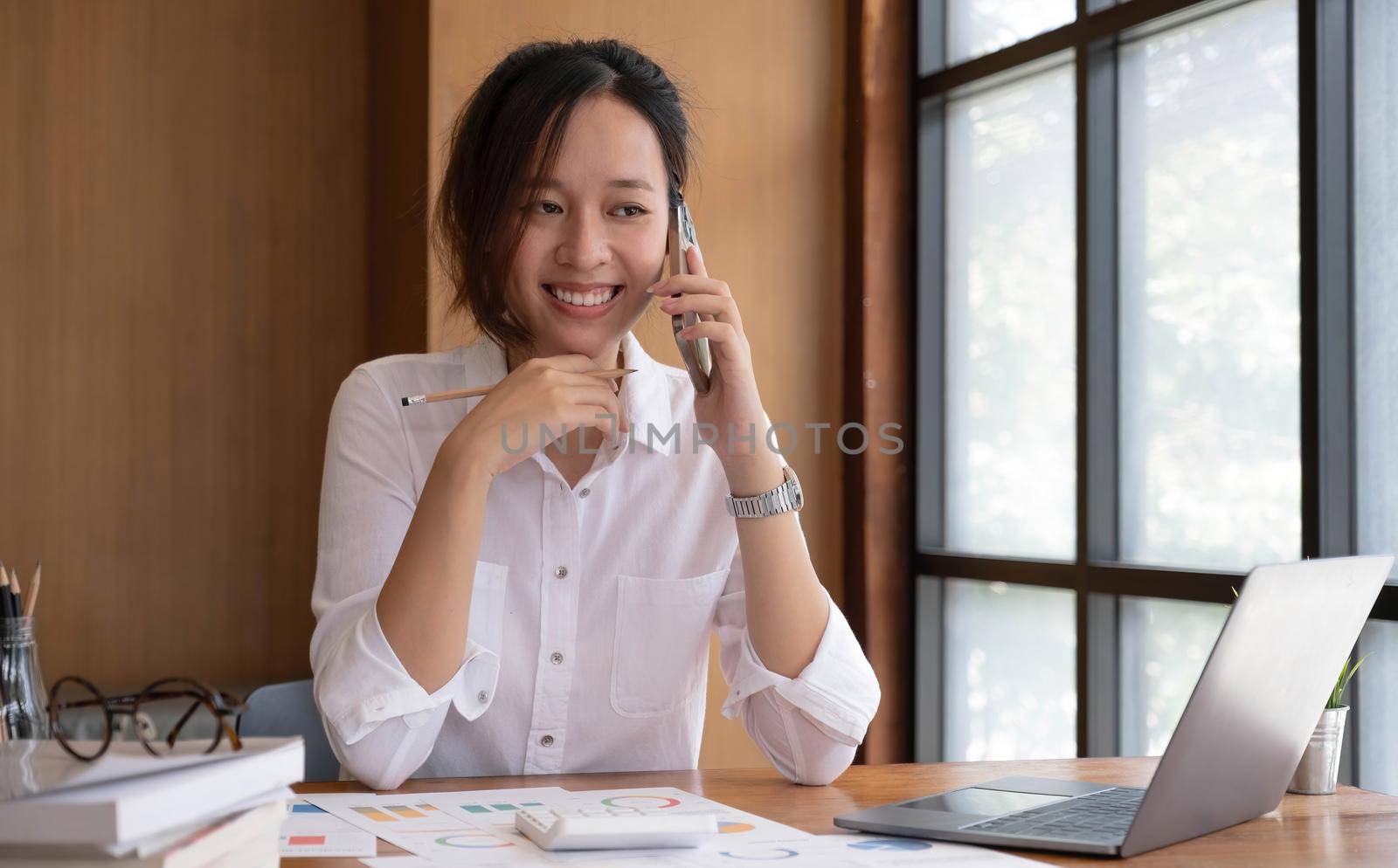 Asian business woman have the joy of talking on the phone, laptop and tablet on the office desk. by wichayada