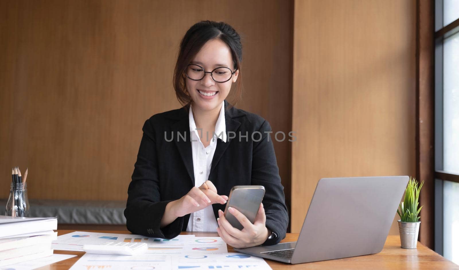 Young asian businesswoman beautiful charming smiling and using on mobile phone in the office..