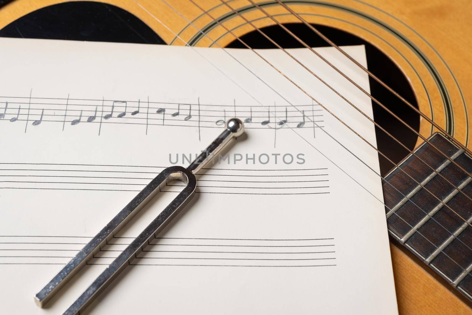 acoustic guitar tuning music sheets and tuning fork close up by Robertobinetti70