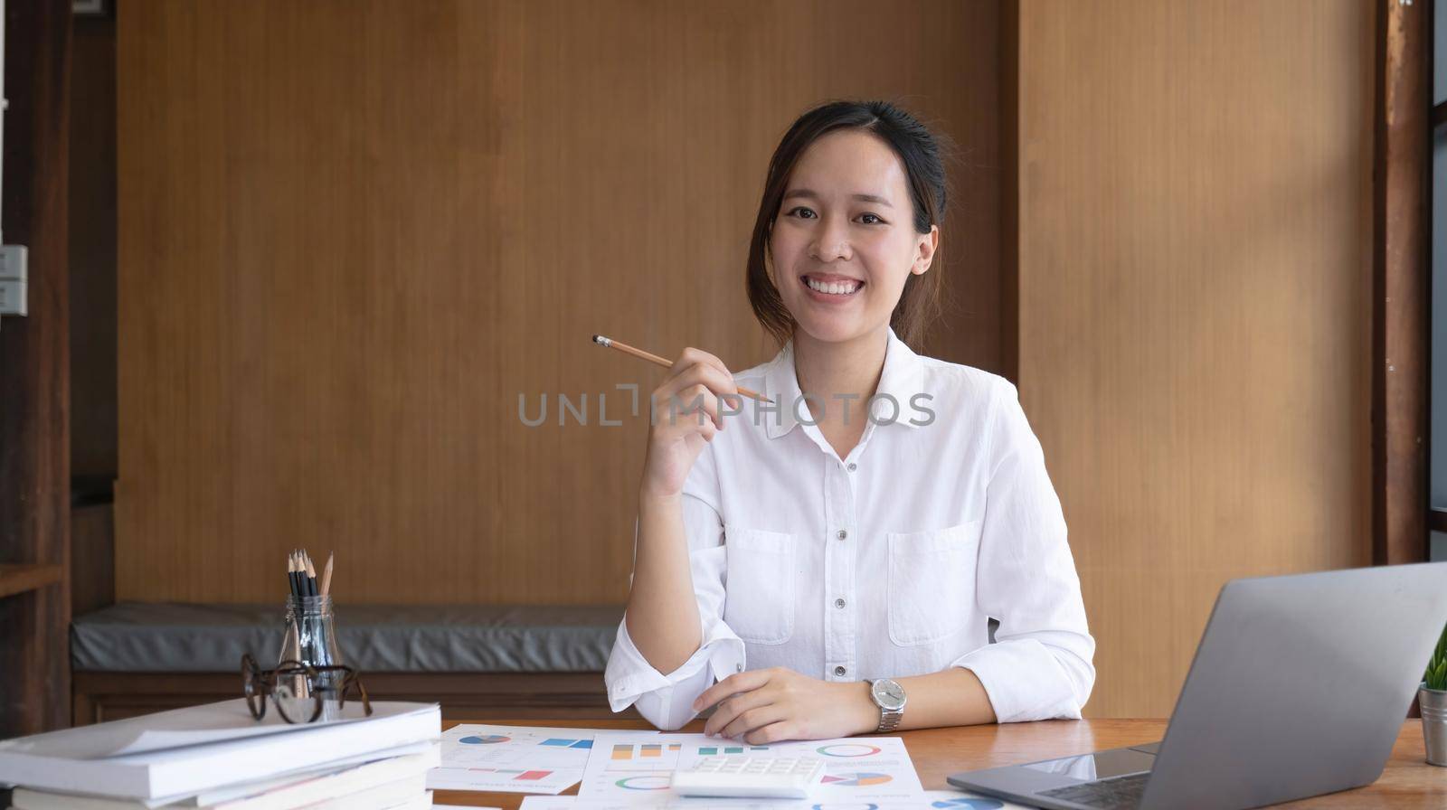 Charming Asian woman working at the office using a laptop Looking at the camera..