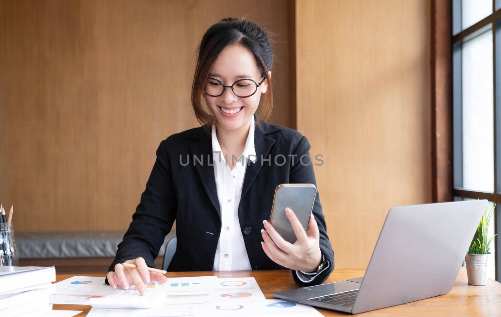 Young asian businesswoman beautiful charming smiling and using on mobile phone in the office. by wichayada