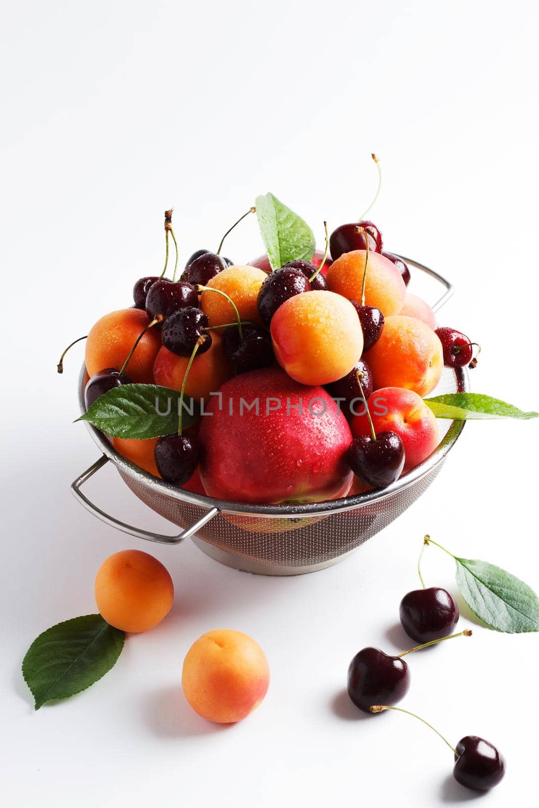 apricots and cherries in a metal bowl on a white background. Copy spase