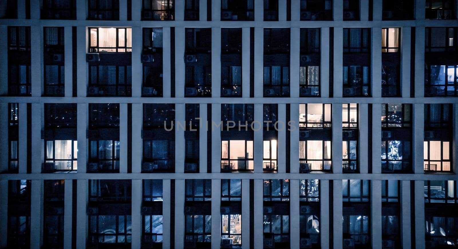 Blinking and flashing windows of the multi-storey building of glass and steel lighting inside. Aerial view of modern residential skyscrapers in downtown by igor010