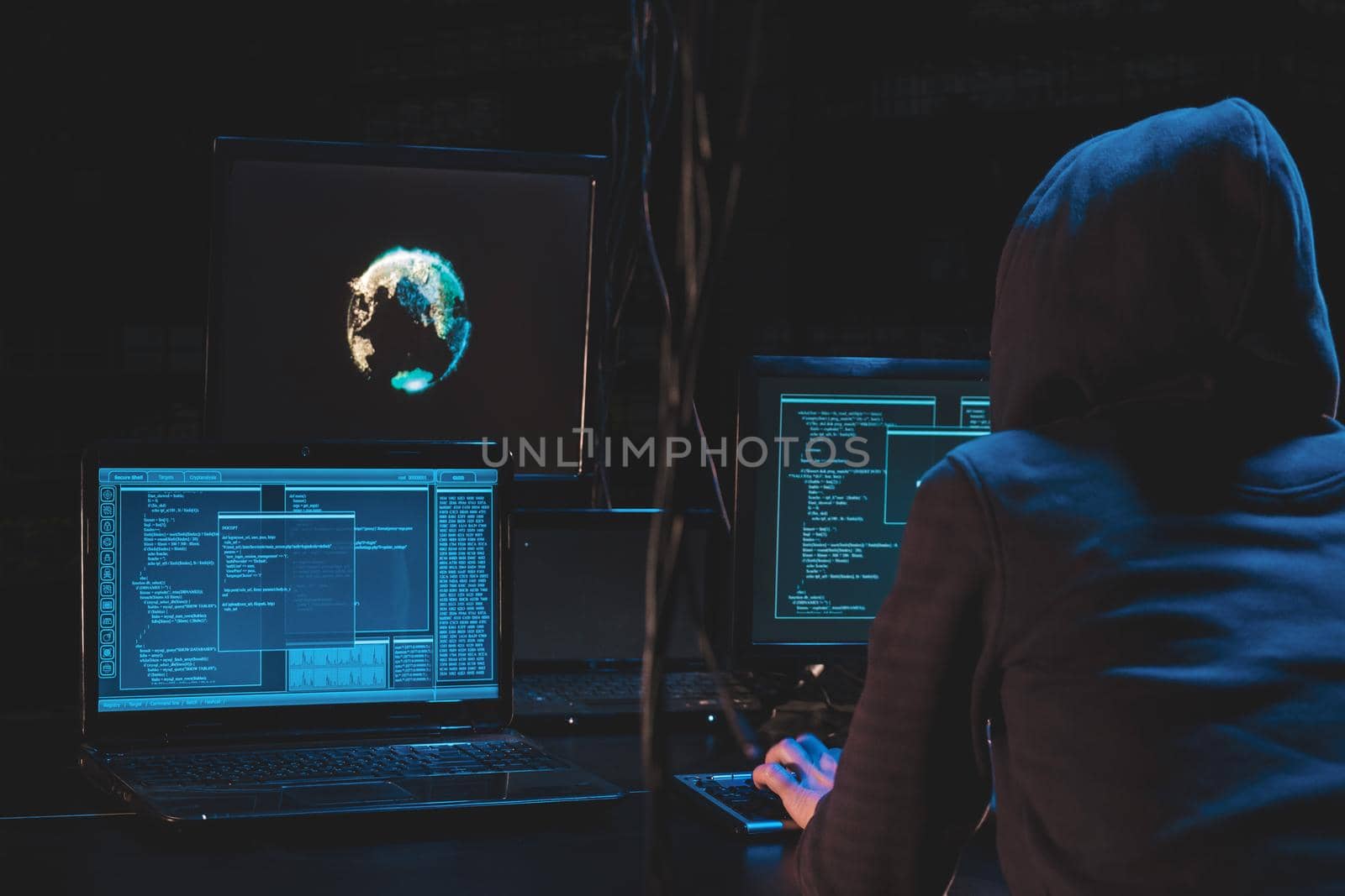 Back hooded hacker using malicious software hack corporate data center. malefactor hidden underground in dark place, multiple displays with phishing code and global map attack.