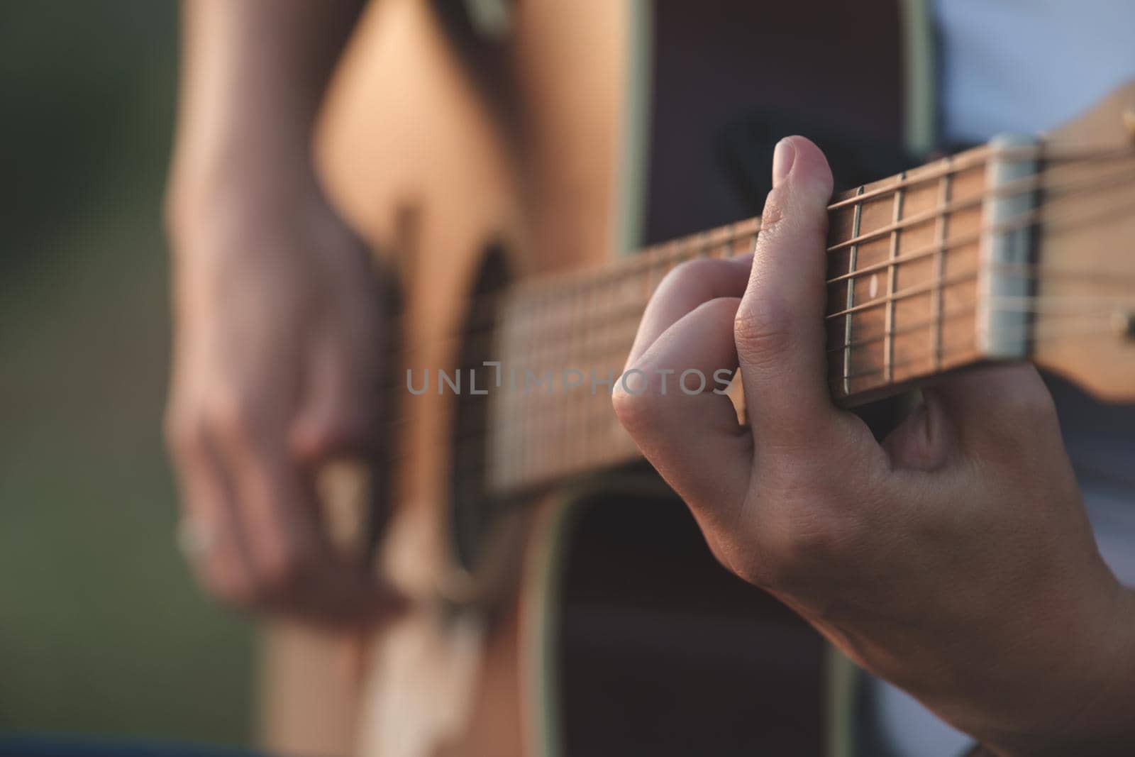 Woman's hands playing acoustic guitar. Musical instrument for recreation or hobby passion concept. Close up of hands playing acoustic guitar by igor010