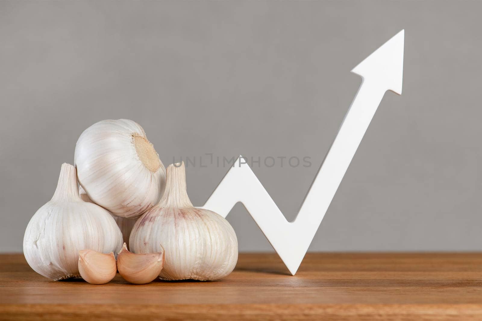 Garlic price, garlic harvest, vegetables export and import. Rising cost of vegetable crops. World food crisis. Bulbs of garlic lie on the table, the graph of the diagram points, up