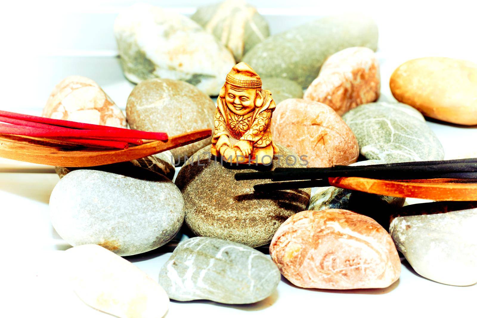 Think deeply or focus ones mind for a period of time, in silence, for religious or spiritual purposes or as a method of relaxation.Statuette of a Buddhist monk among incense and various stones
