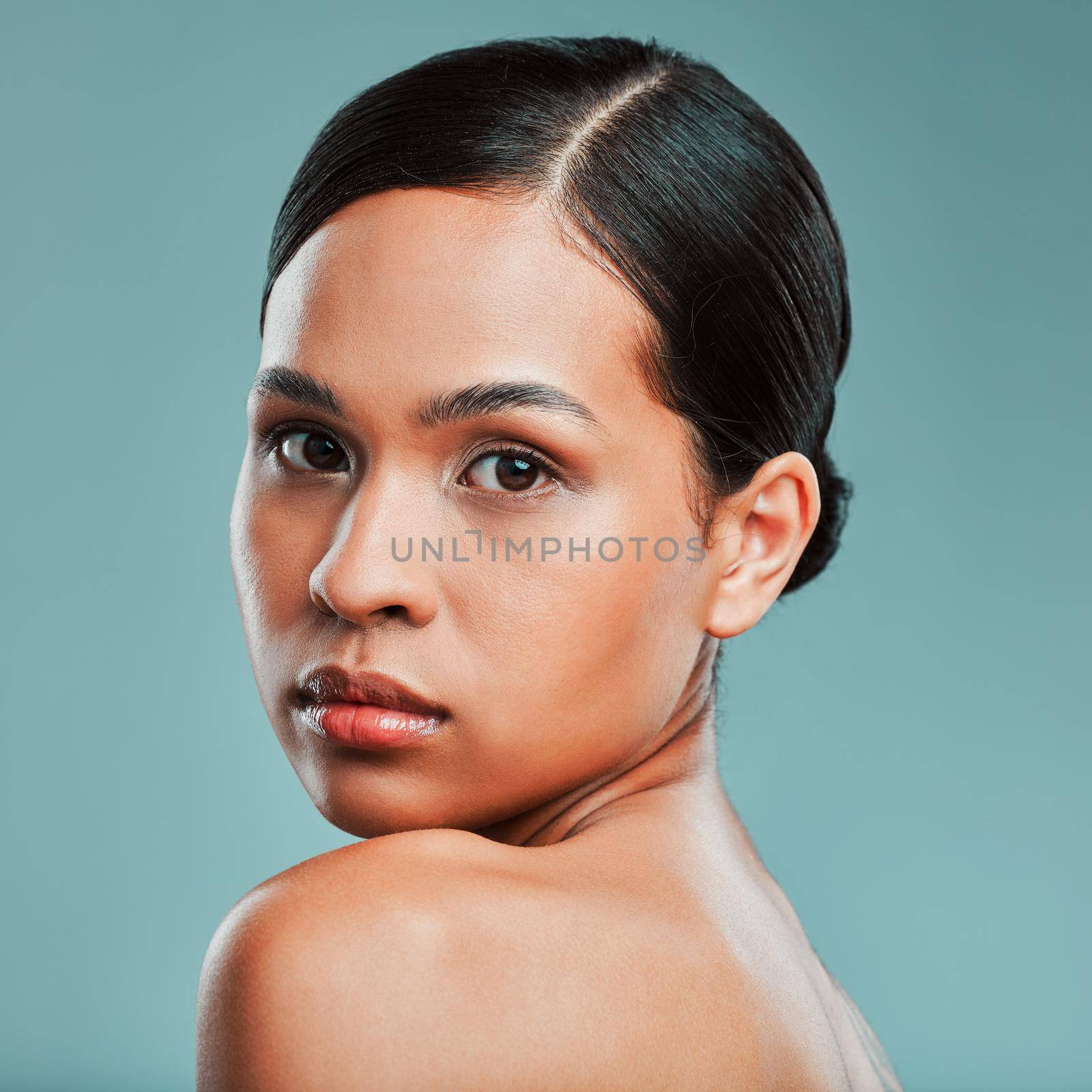 Portrait of a young beautiful mixed race woman with smooth soft skin posing against a green studio background. Attractive Hispanic female with stylish makeup posing in studio.
