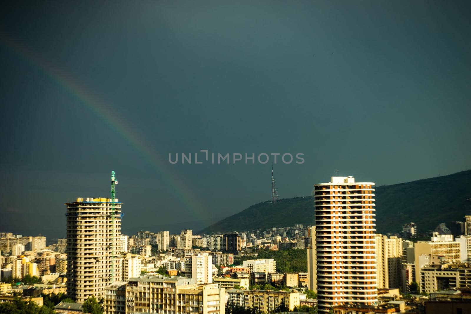 Heavy storm weather with rainbow over the downtown of Tbilisi, capital city of Georgia