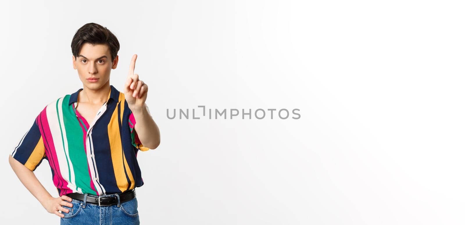 Disappointed young man prohibit something, shaking finger in disapproval, forbid you, standing over white background.
