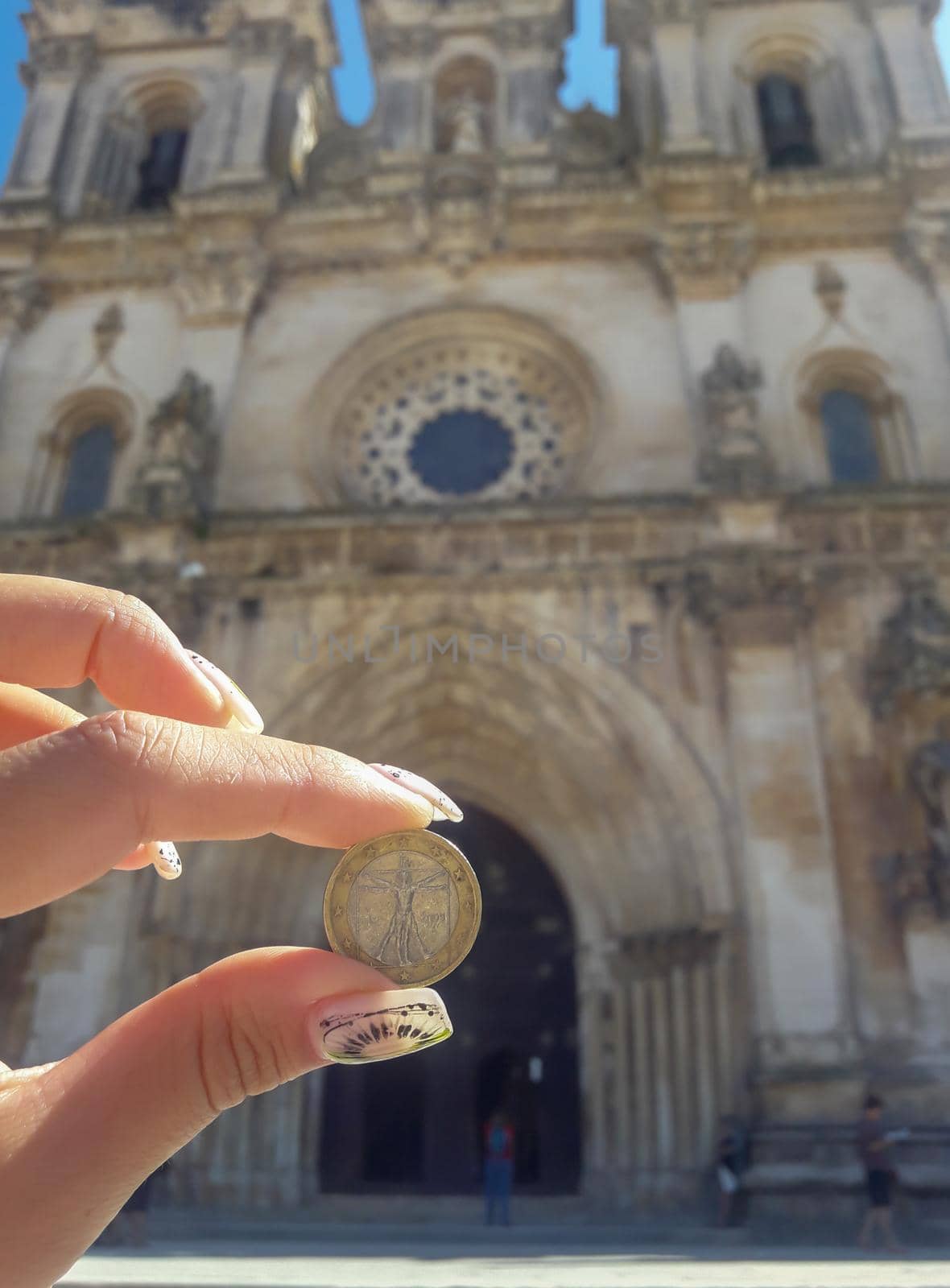 hand holding a coin with image of Vitruvian Man on the background of an old building. download photo