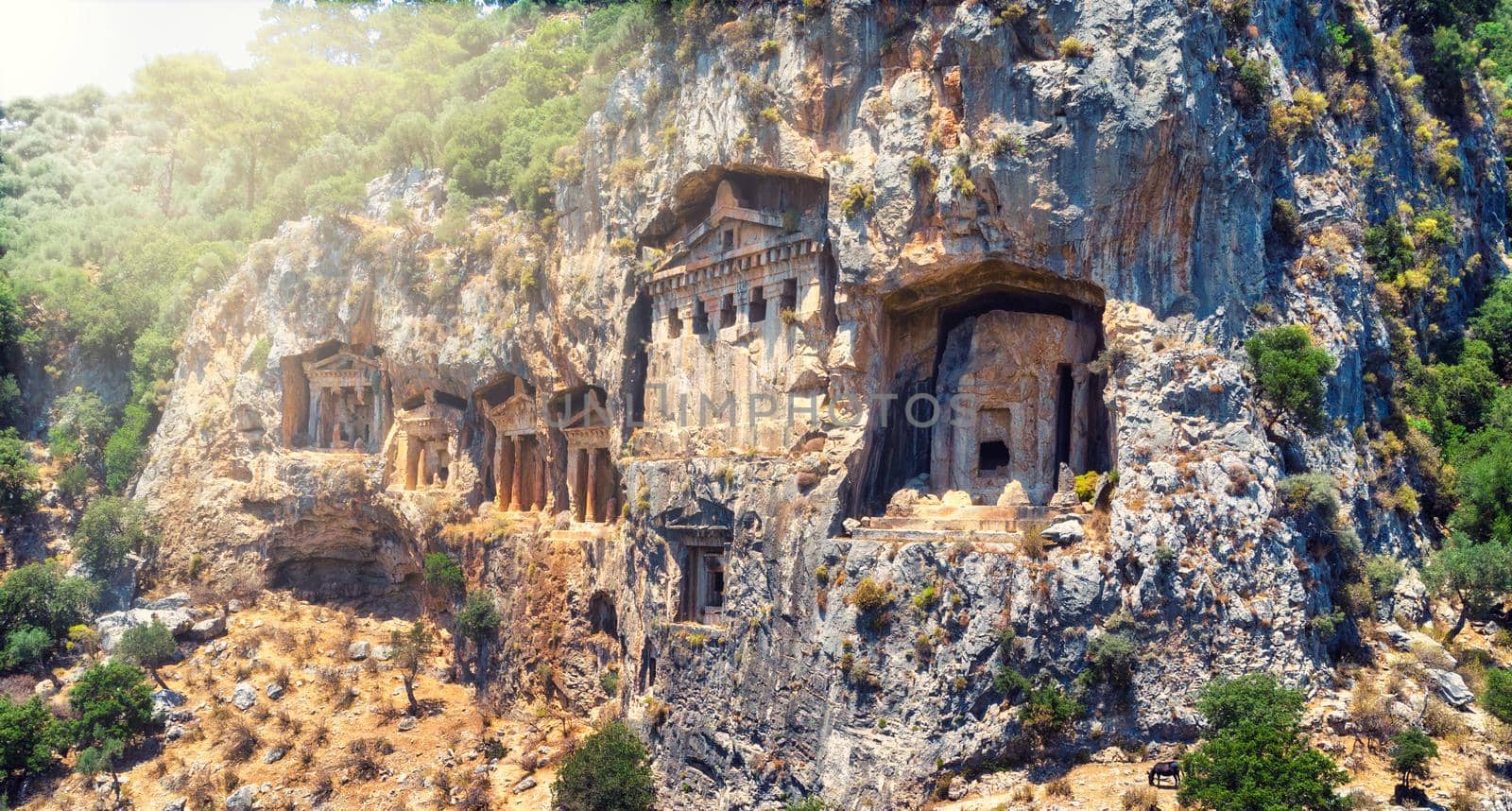 The ancient ruins of Myrna city close to Antalya Turkey, with creepy rock tombs lightened by sun going down. by igor010