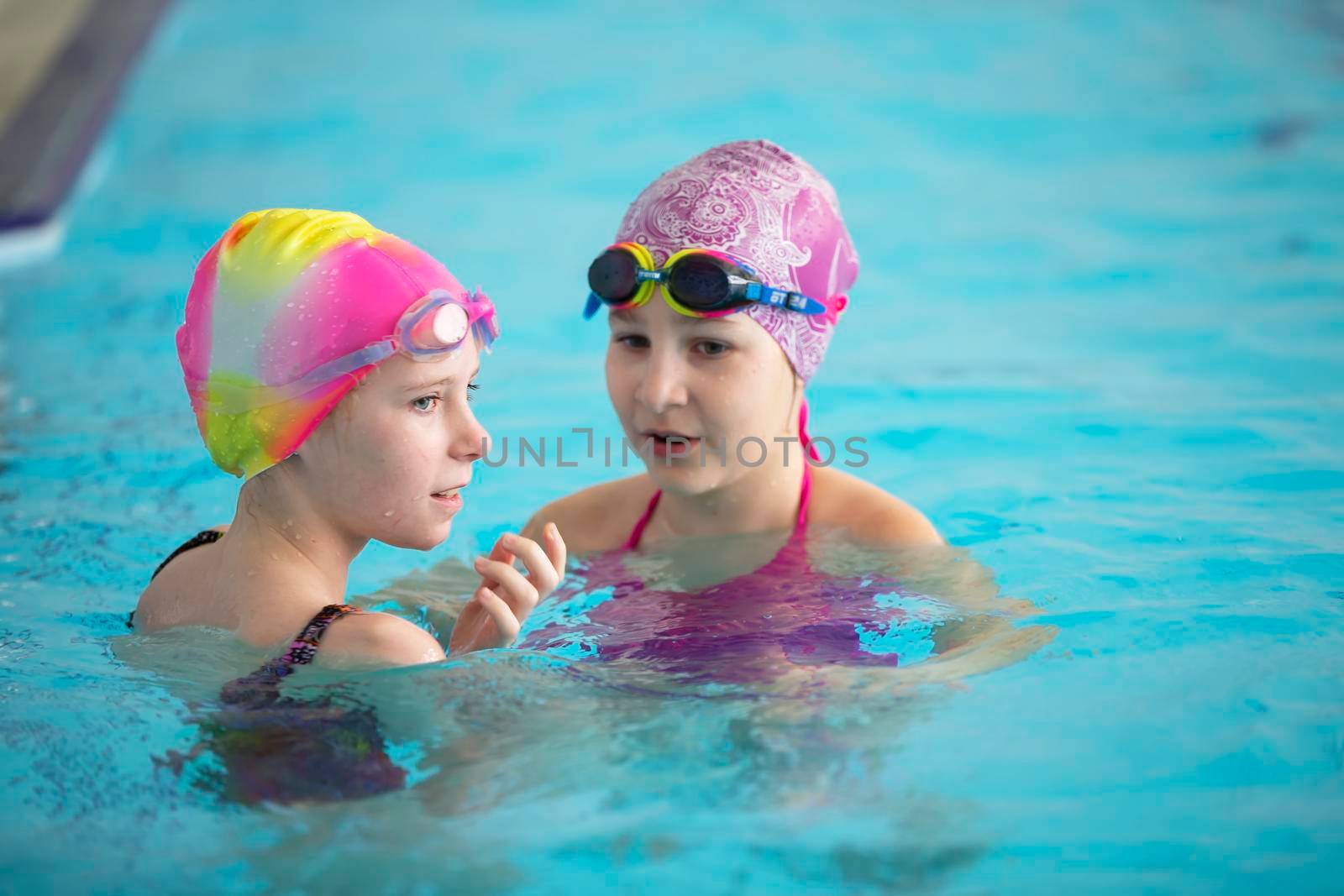 Two girls in swimming caps in the pool. Swimming section. by Sviatlana