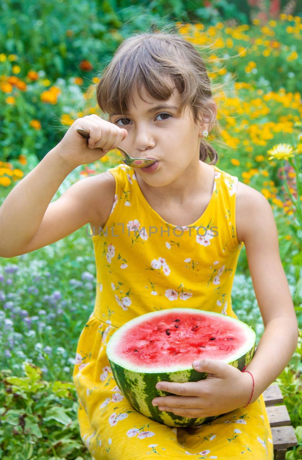 The child eats a watermelon with a spoon. Selective focus. by yanadjana