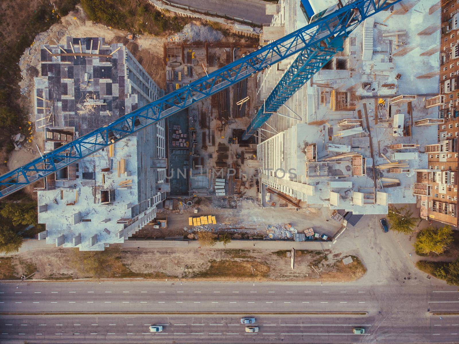 Contstruction Site from above. Aerial view of new apartment under construction. Top view of building at the road. Under construction site, crane, and car traffic transportation. Download high quality photo