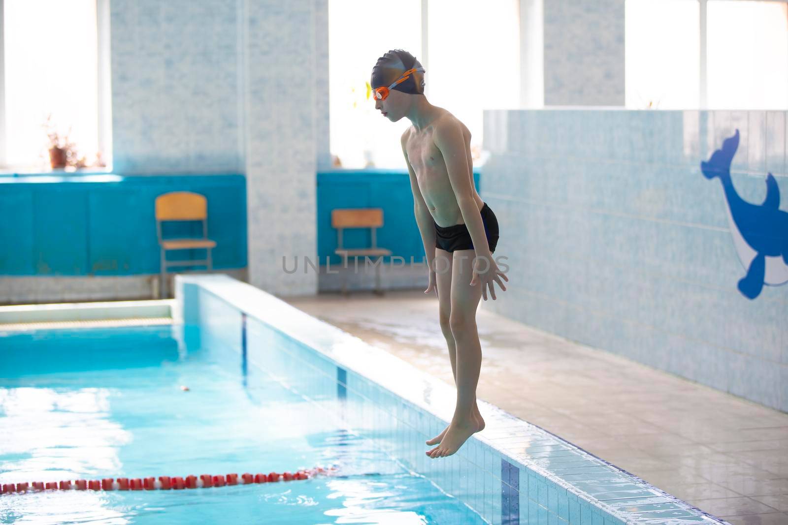 A boy in a swimming cap is jumping in a sports pool.