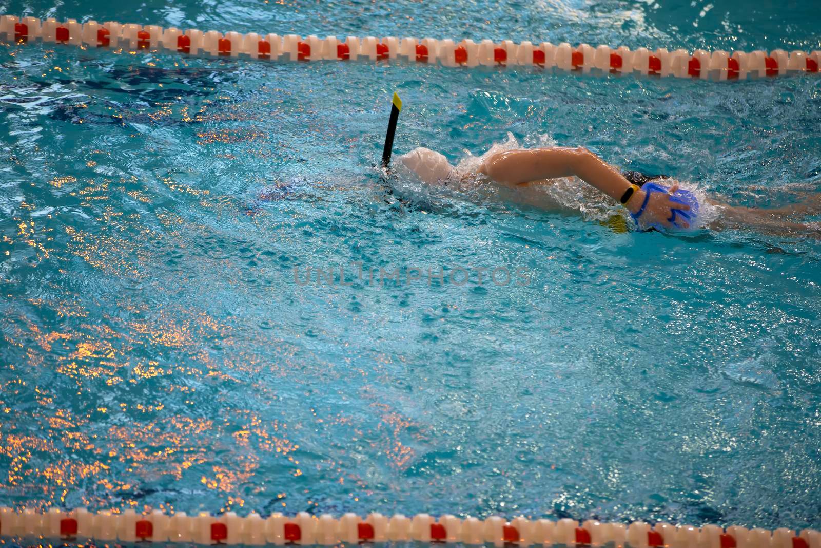 Child athlete swims in the pool. Swimming section.