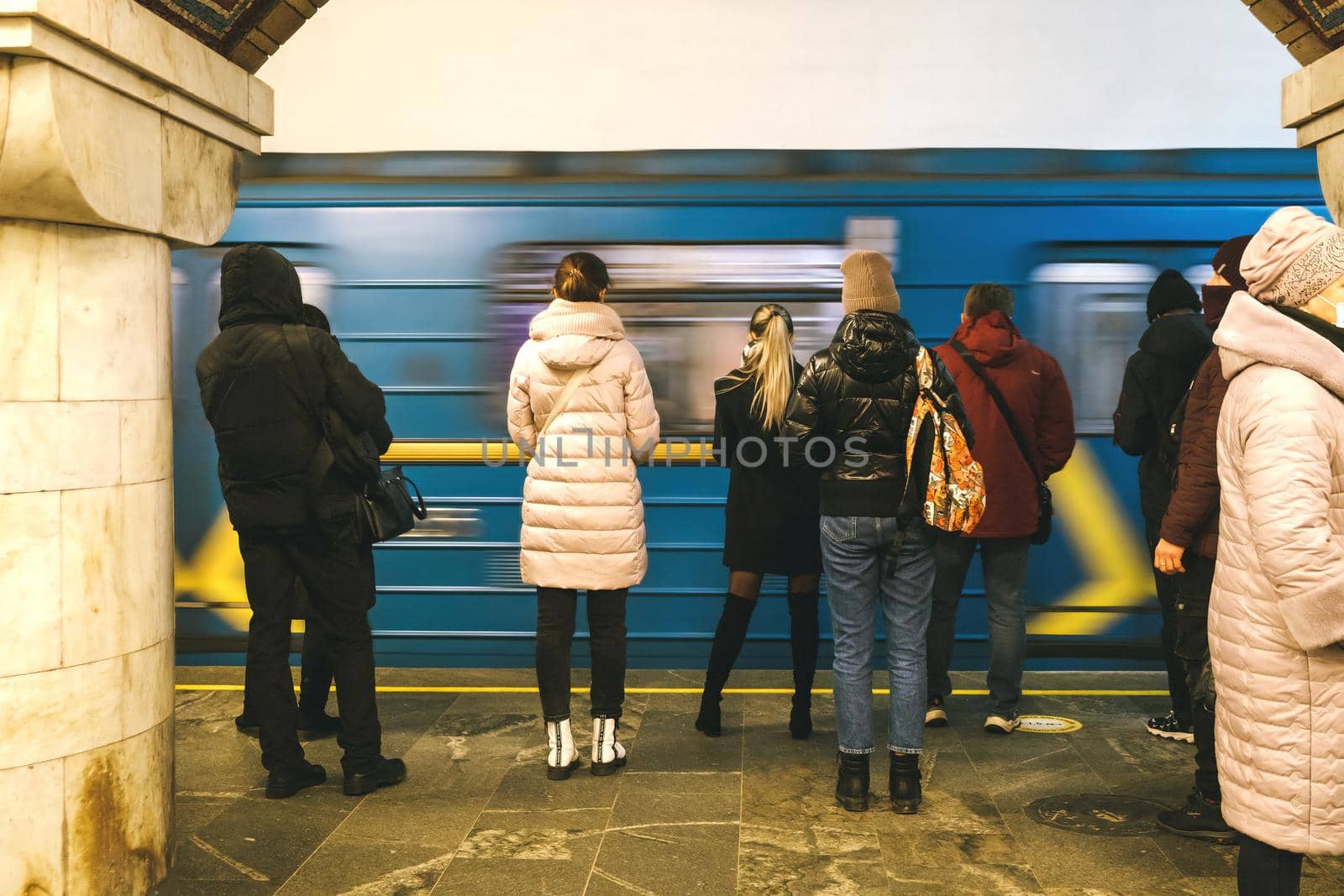 People on a subway platform on the background of a passing train underground. adult people standing on metro platform, train in motion. Way to work. Morning commute. Urban life. download photo