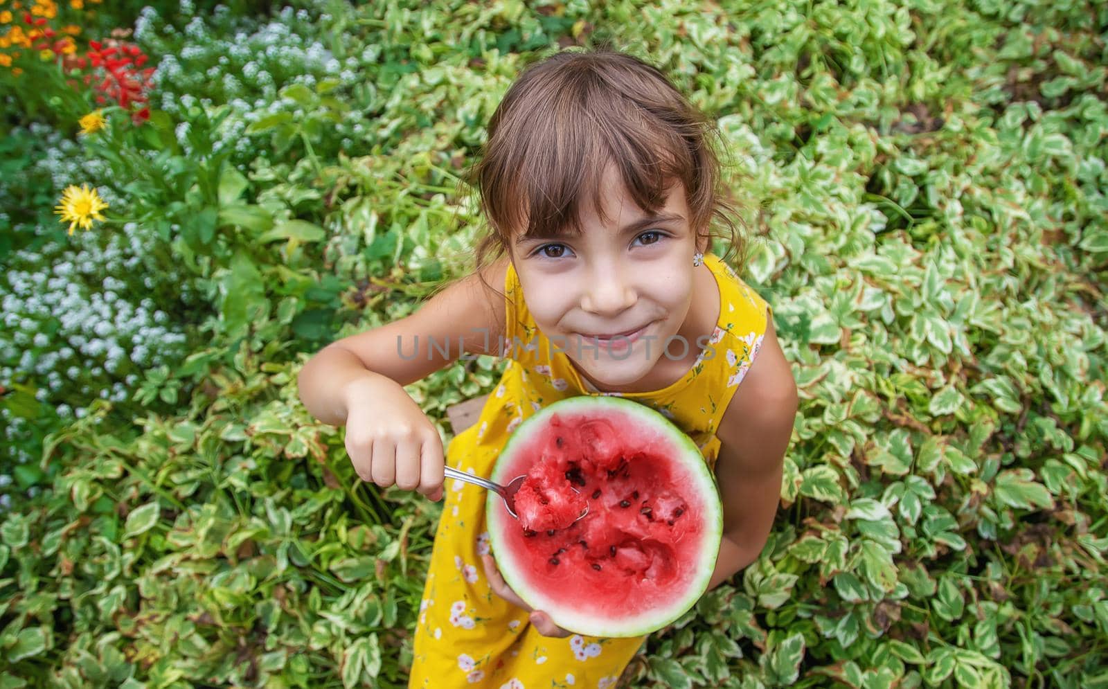 The child eats a watermelon with a spoon. Selective focus.