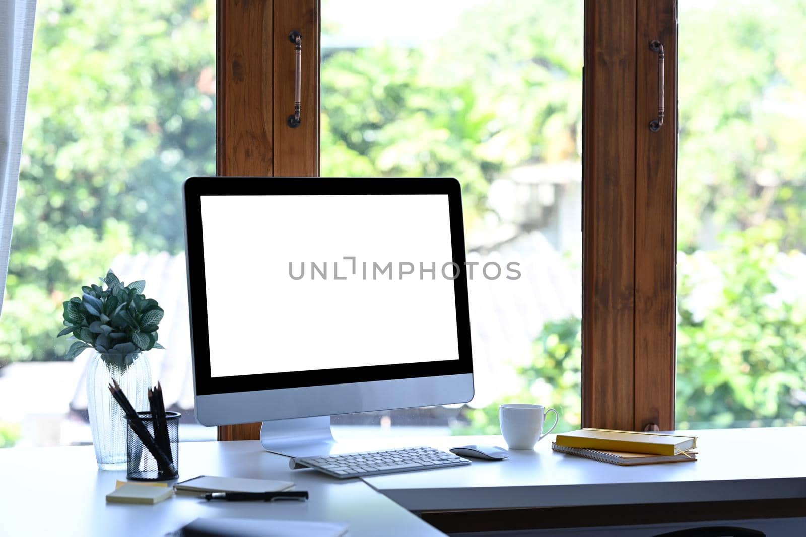 Mockup computer with blank screen and office supplies on white table at creative workplace. by prathanchorruangsak