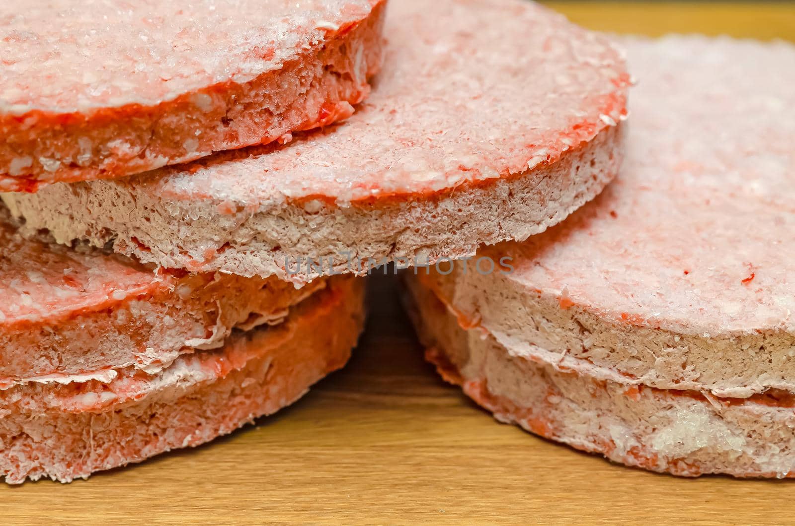 frozen beef hamburger patties, defrost before grilling, stacked on the counter.