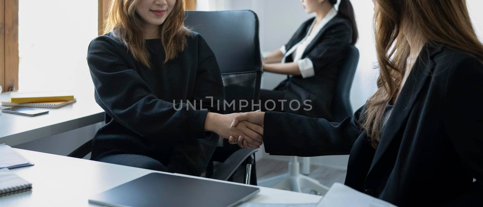 Two sucsessful businesspeople shaking hands after negotiations or finishing up meeting. by prathanchorruangsak