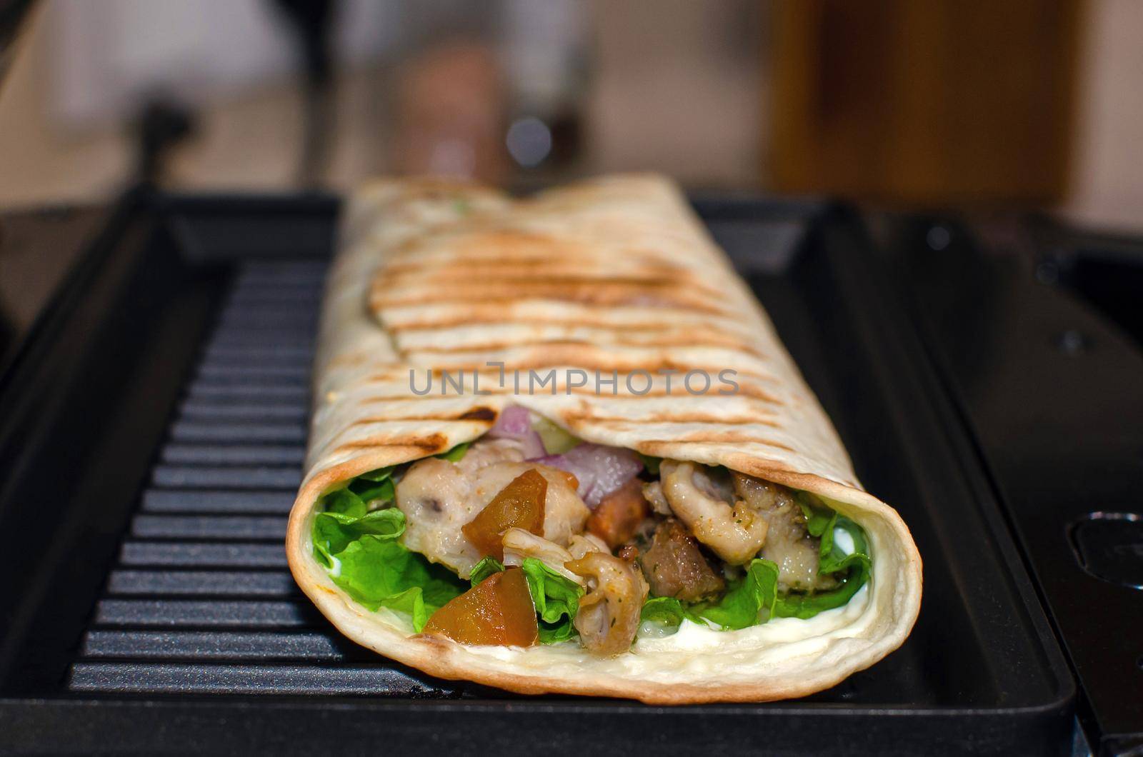 Roll of pita bread, vegetables and chicken. Cooking on an electric grill. Kebab, shawarma