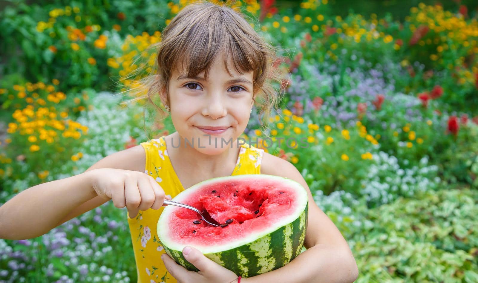 The child eats a watermelon with a spoon. Selective focus.