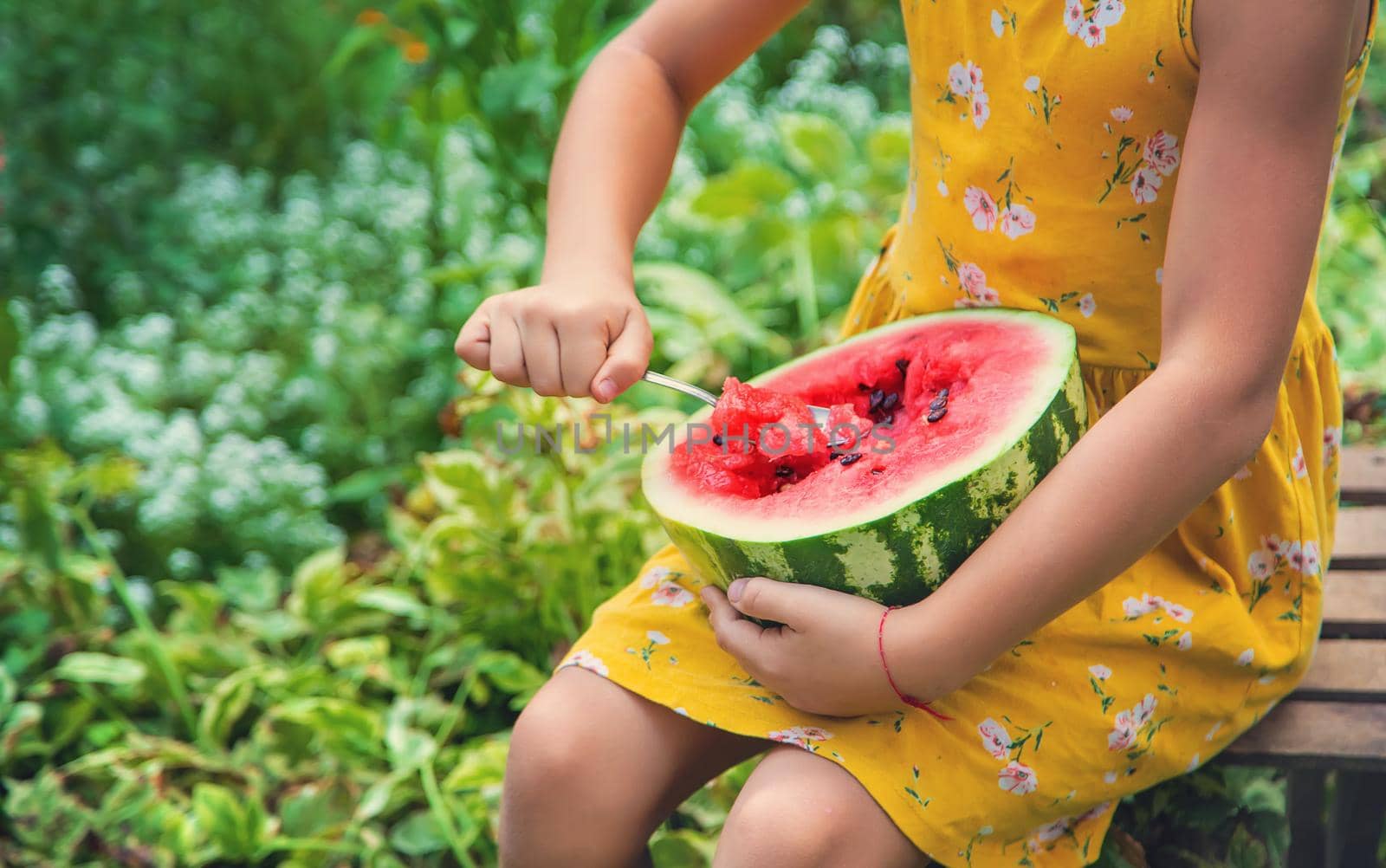 The child eats a watermelon with a spoon. Selective focus. by yanadjana