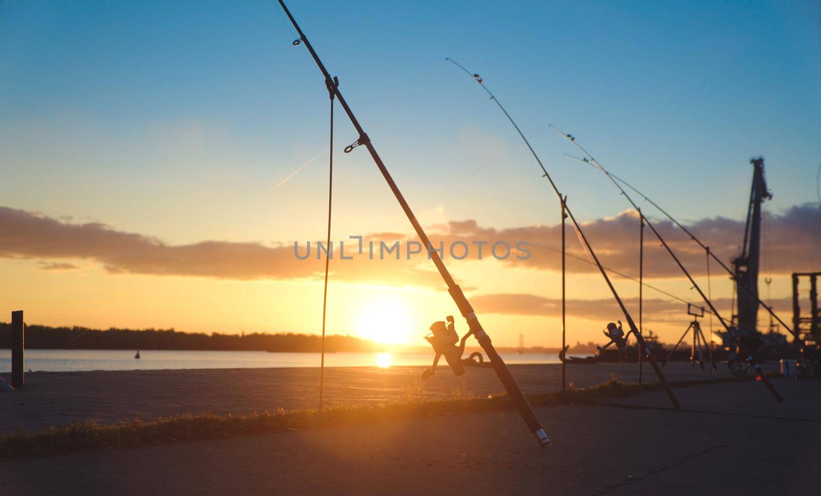 Fishing rod, spinning reel on the background pier river bank. Sunrise. Fog against the backdrop of lake. Misty morning. wild nature. The concept of rural getaway. Article about fishing day. by igor010