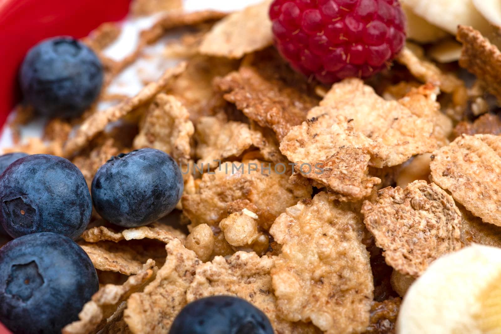 Muesli. Breakfast, healthy food and diet. Muesli with fruits in a plate on a pink background. Blueberries, strawberries and raspberries on a background of muesli flakes. Print banner with copy space.