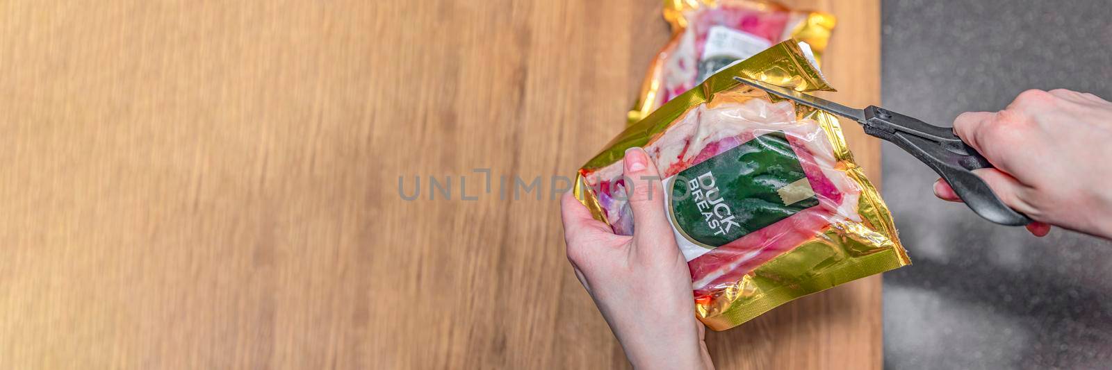 Duck fillet in vacuum. Duck meat in vacuum plastic packaging on a wooden cutting board, background for a culinary theme, place for text. by SERSOL