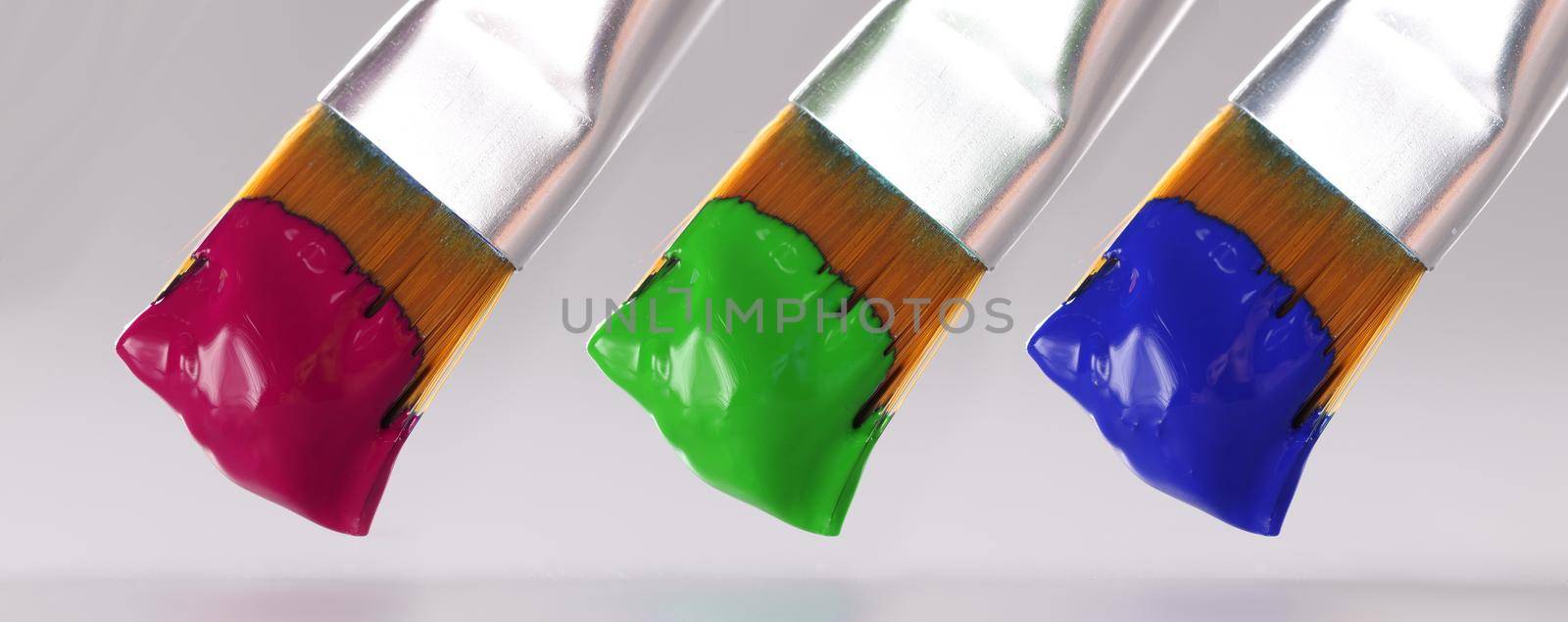 Three brushes with different paint colors. Artistic paints of different colors concept