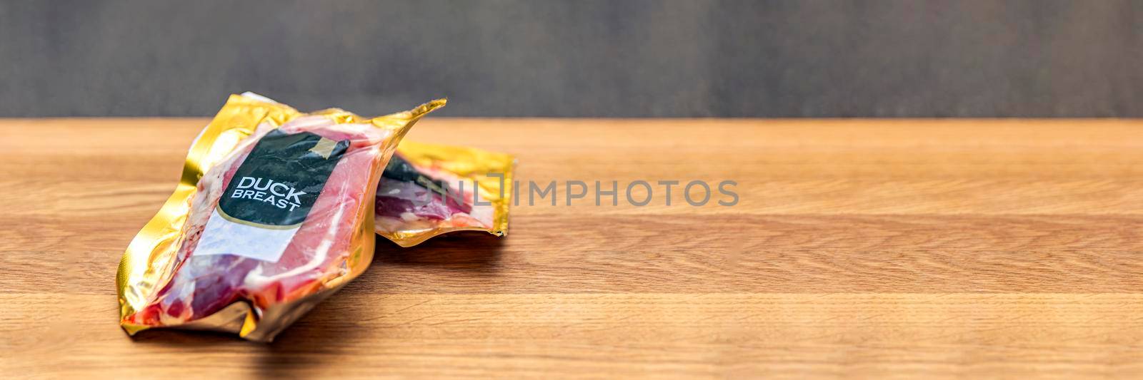 Vacuum packed duck breast. Duck meat in vacuum plastic packaging on a wooden cutting board, background for a culinary theme, place for text. Copy space