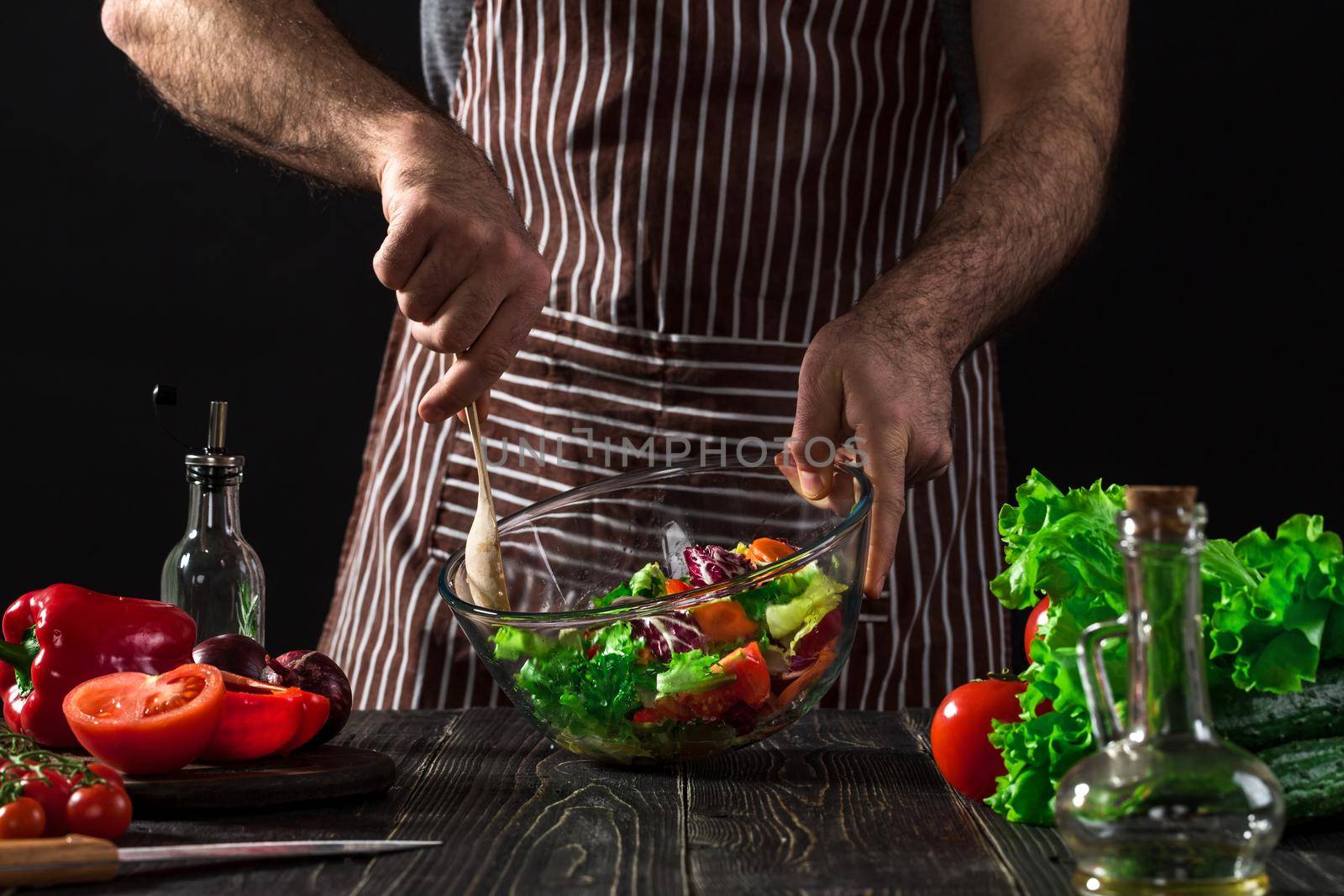 Man preparing salad with fresh vegetables on a wooden table. Cooking tasty and healthy food by nazarovsergey