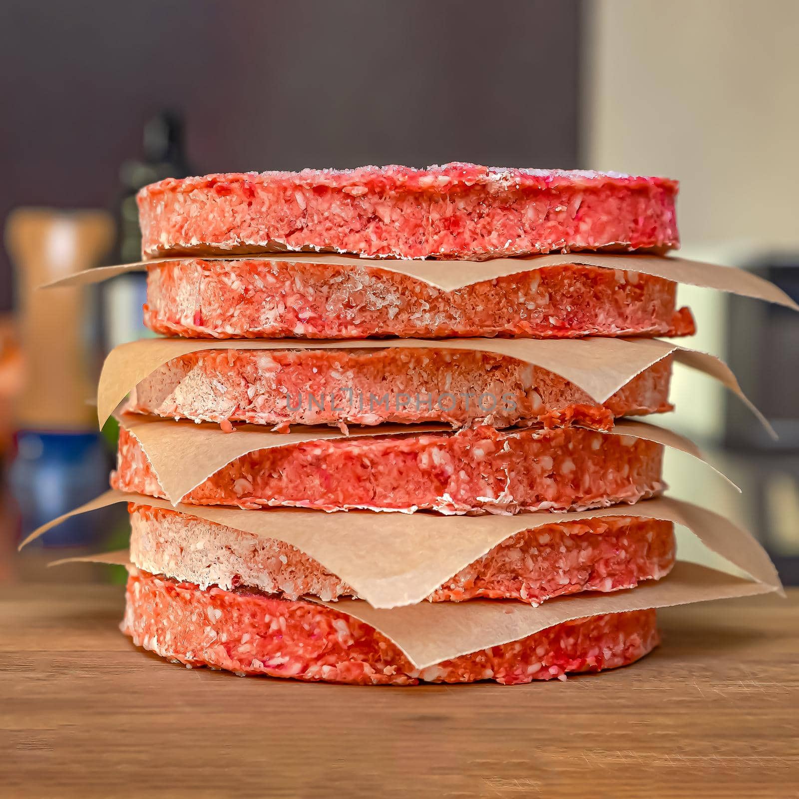 Frozen beef burger patties are placed on a wooden cutting board before cooking. Freezing in the freezer