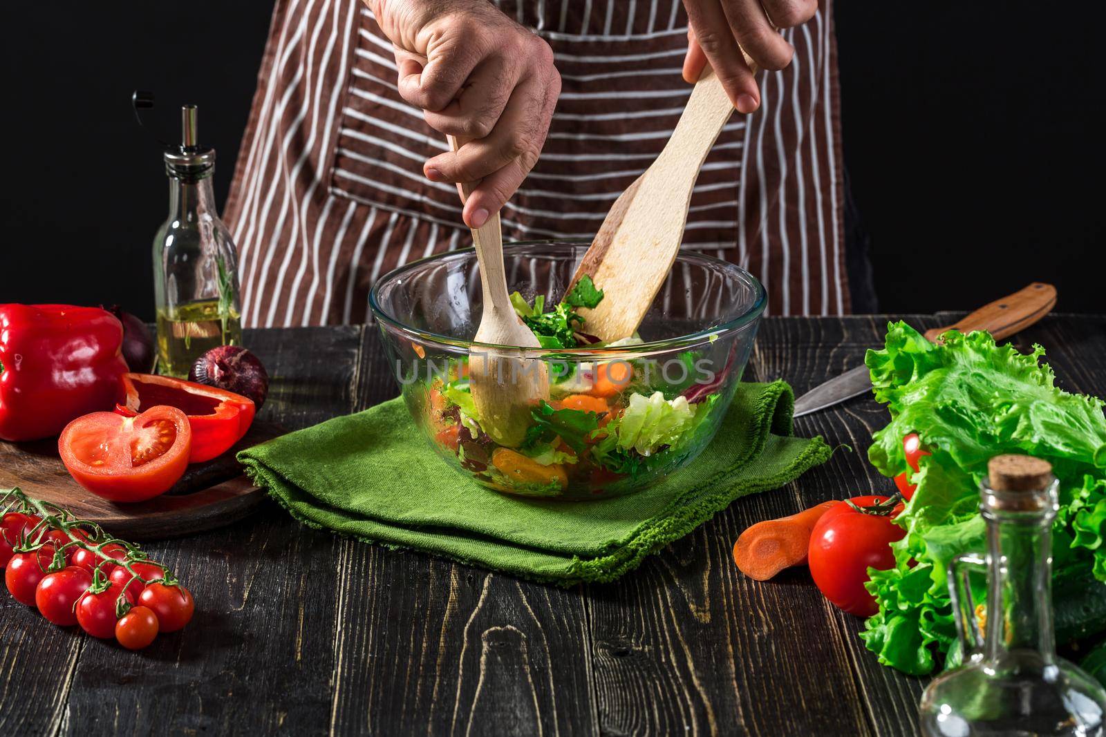 Man preparing salad with fresh vegetables on a wooden table. Cooking tasty and healthy food by nazarovsergey