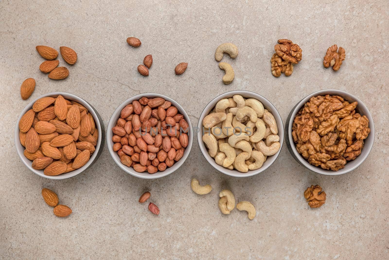 Nut background. Banner for large format printing, advertising and website design. Nuts of different varieties lie in bowls on a stone countertop, top view. Peanuts, cashews, almonds, walnuts