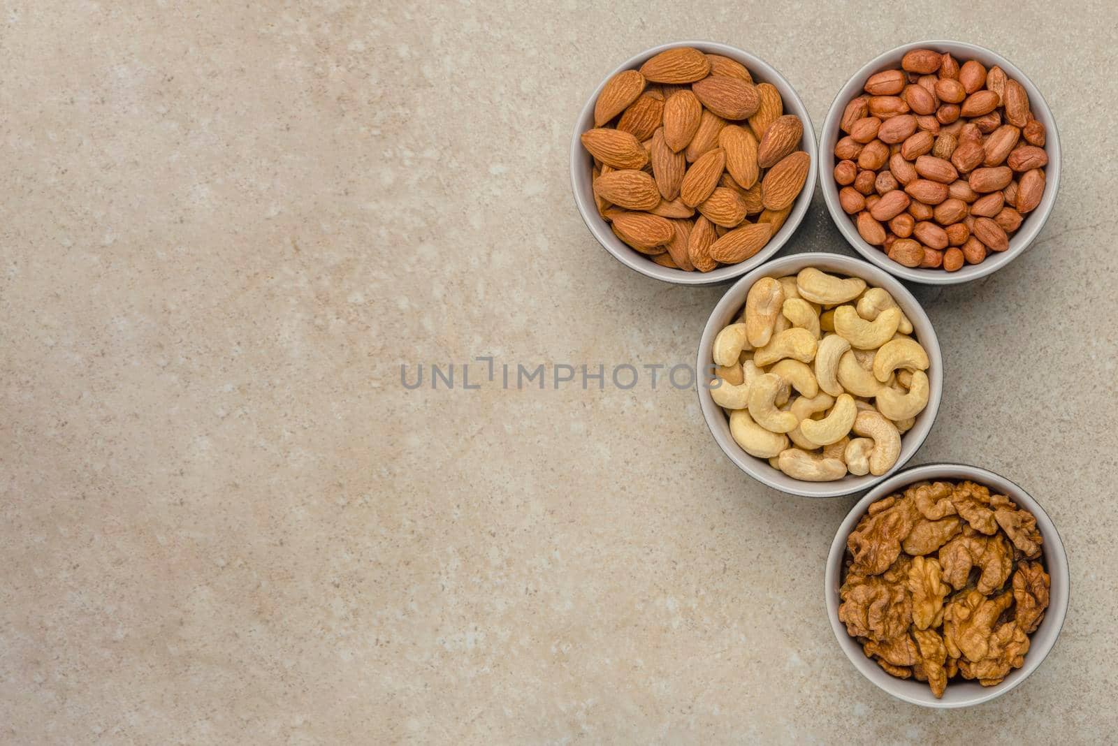 Nuts of different varieties, top view. The mixed nuts lie in bowls on a stone countertop. For design and printing. Place to insert text, recipe or entry