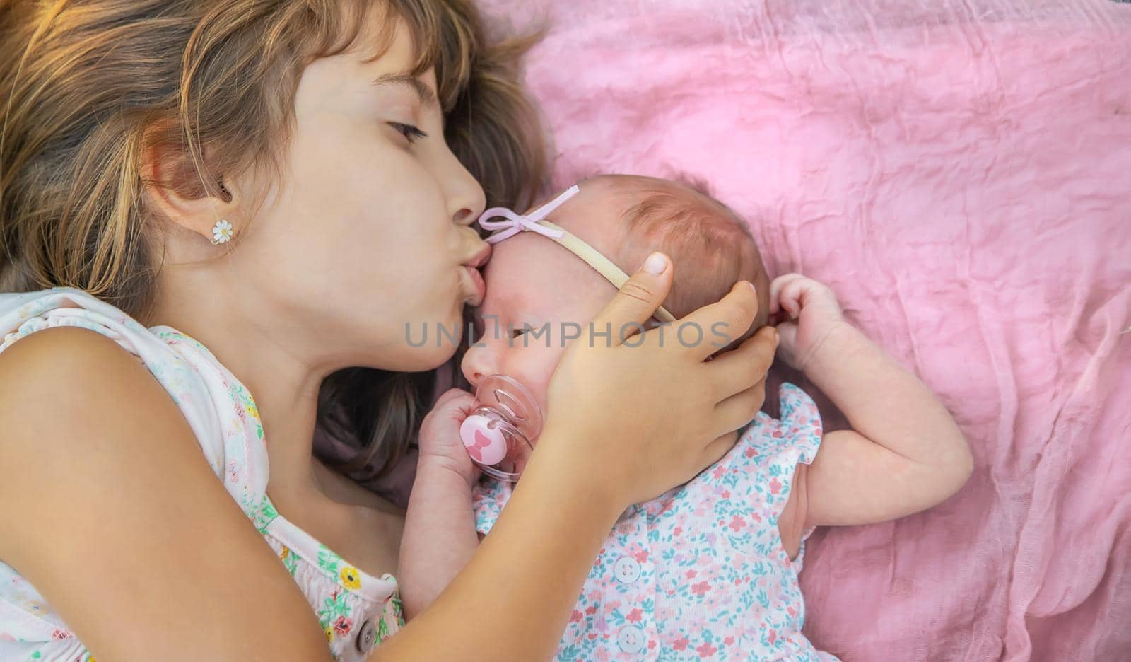 The older sister holds the newborn in her arms. Selective focus. People.