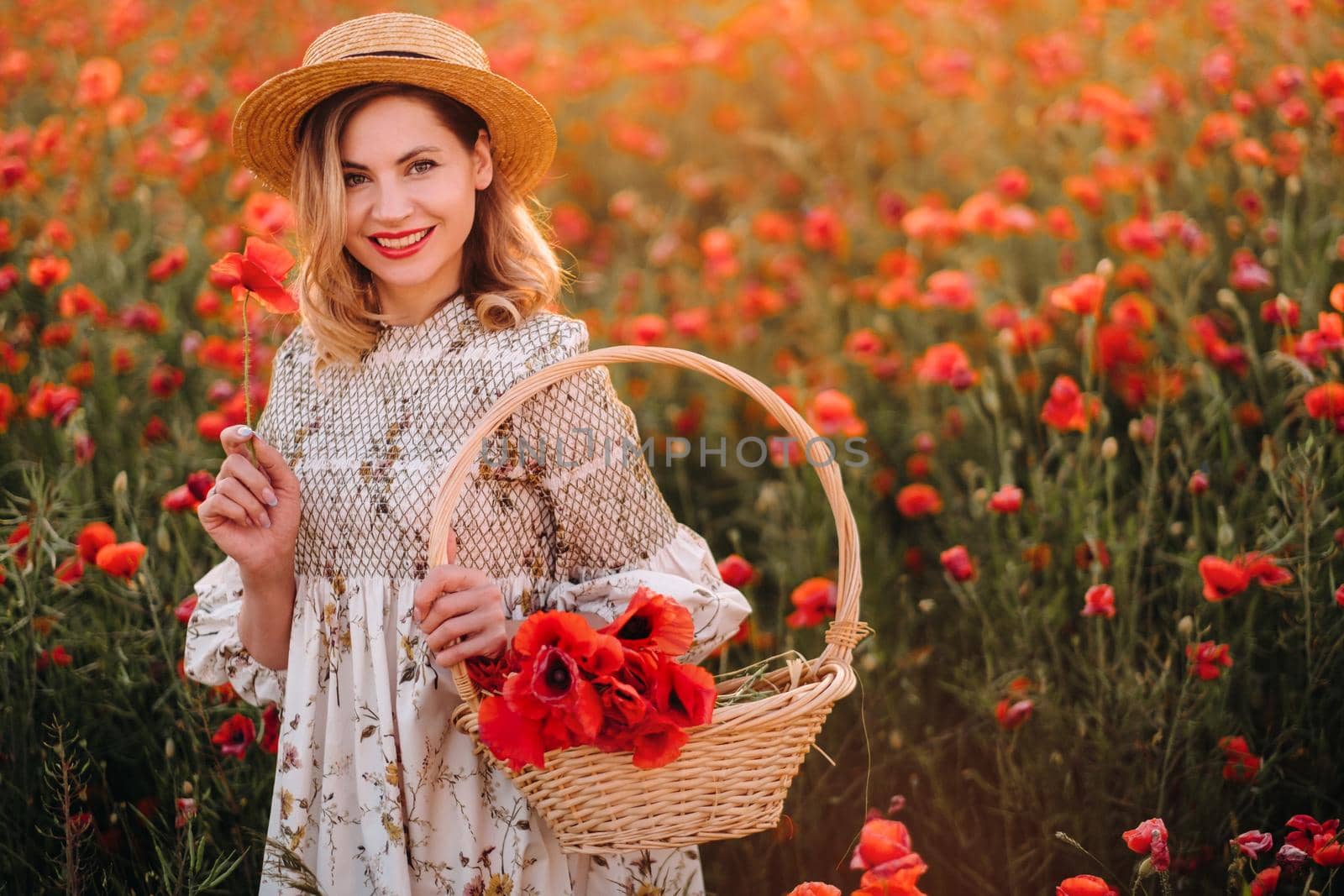 a girl in a dress with a hat and with a basket in a field with poppies.